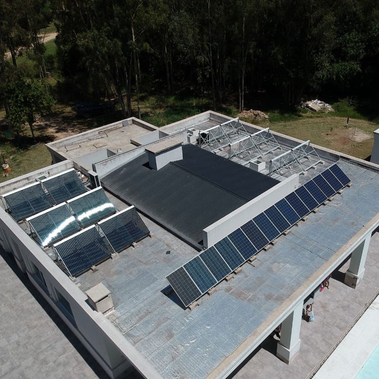 Vista desde arriba de una terraza con colectores de tubos para agua caliente y una larga fila de paneles.